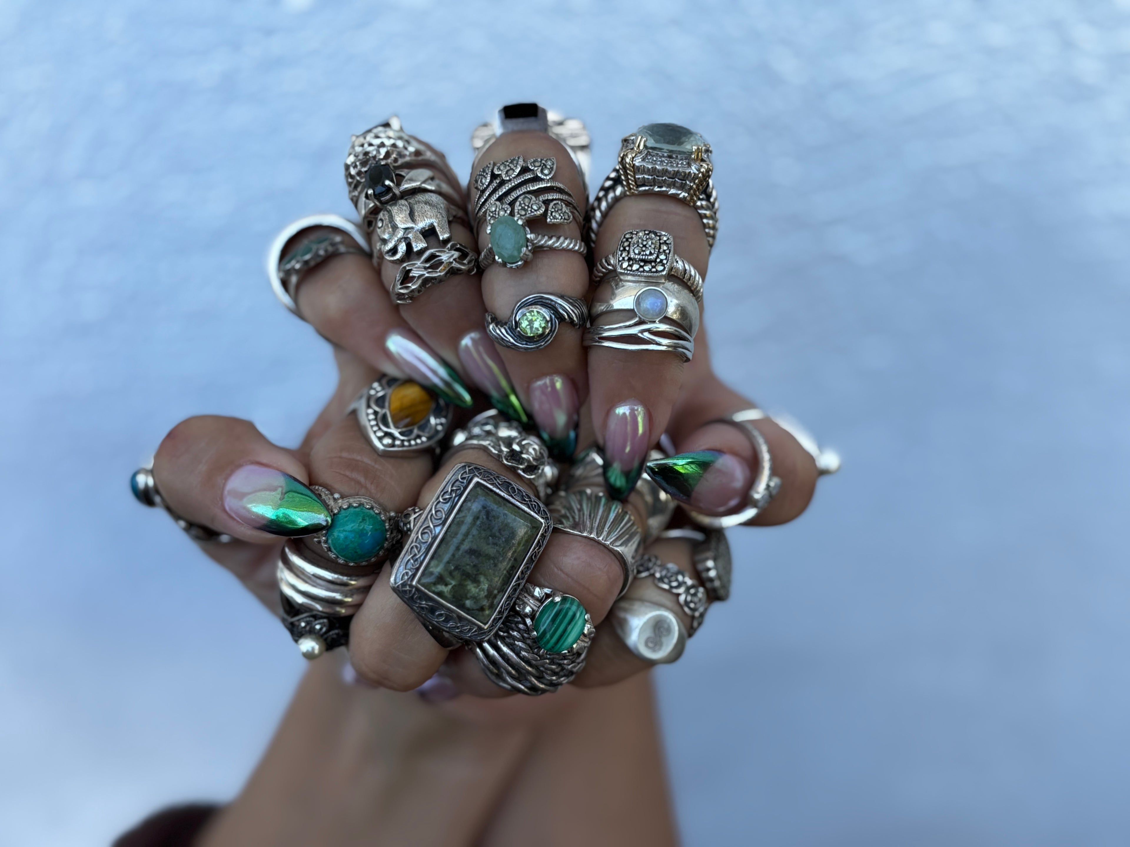 Two freshly manicured hands with multiple sterling silver rings on every finger