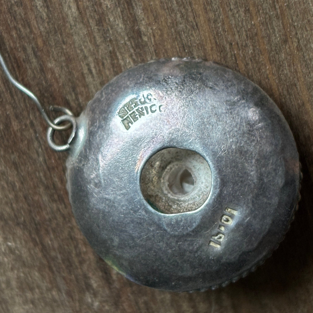Close-up of the back of a sombrero earring showing the STERLING MEXICO stamp and an additional letter-number registration mark.