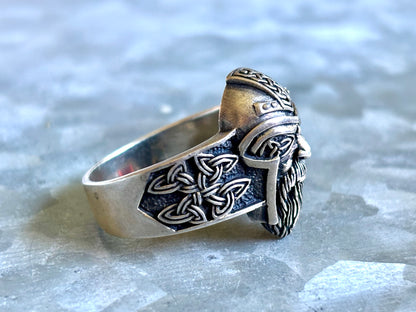 Side profile of Viking-inspired silver ring showing raised knotwork, tapered band, and projecting warrior face.