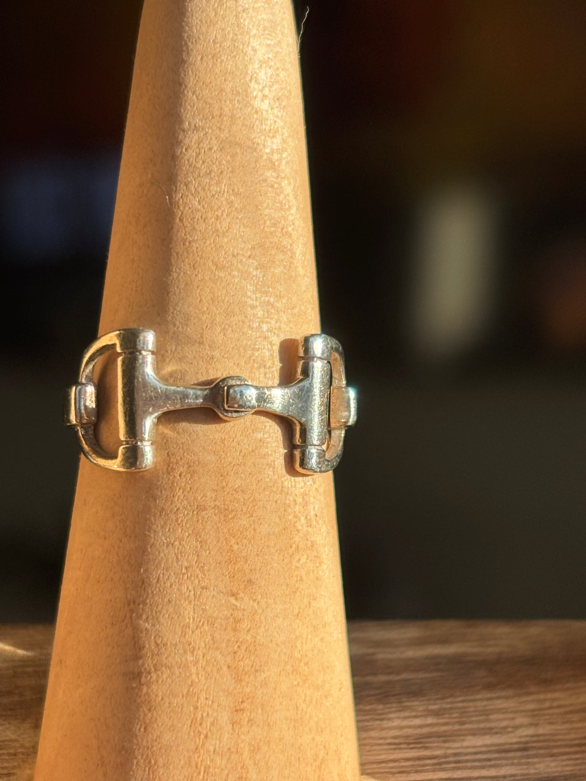 sterling silver horsebit ring showing the open stirrup-shaped detail and slim polished band shown displayed on a ring stand