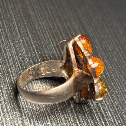A vintage silver ring featuring three amber-colored gemstones in a floral cluster setting, showing the inside hallmarks
