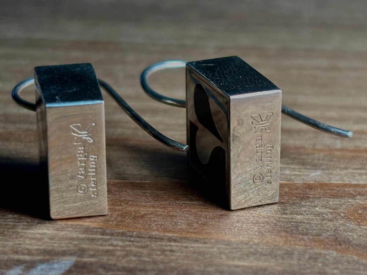 Close-up of Vargas sterling silver earrings showing the © Vargas signature, sterling stamp, and designer symbol.