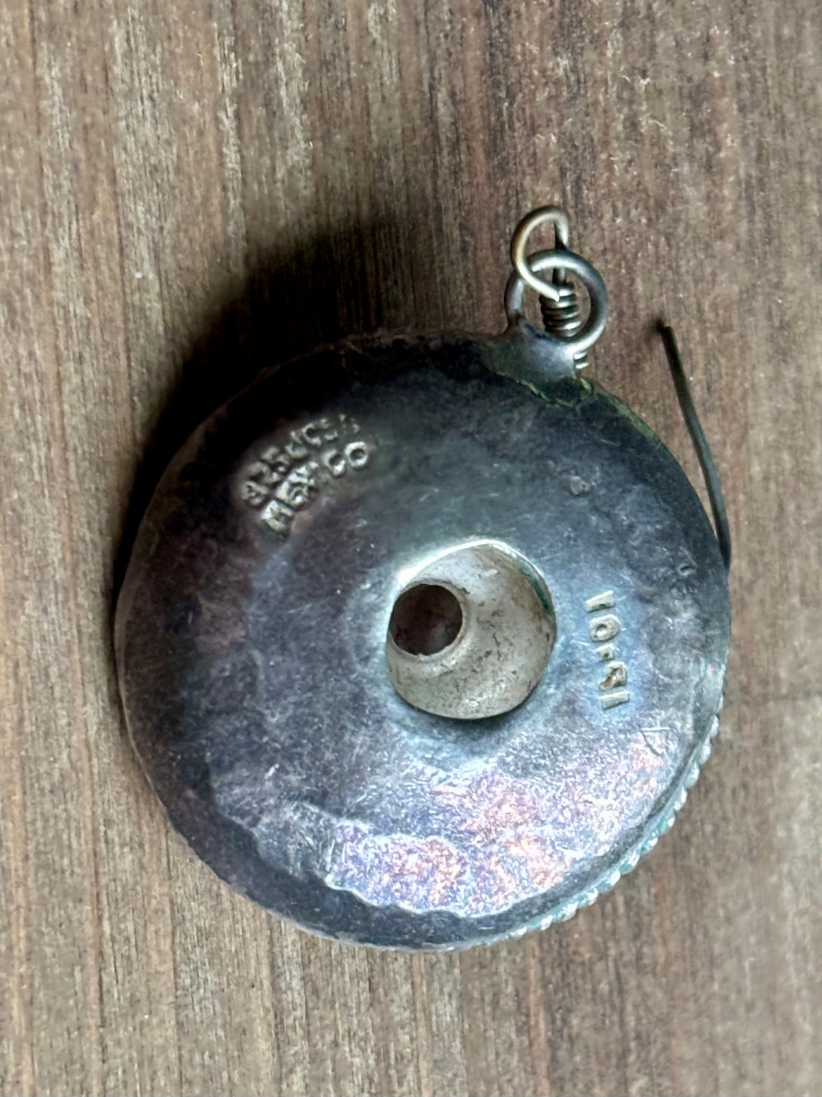 close-up of the back of a sombrero earring showing the MEXICO stamp and an additional letter-number registration mark.