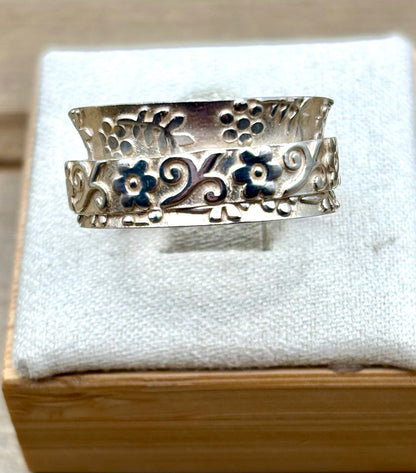 Silver ring with floral design on a white cushion 